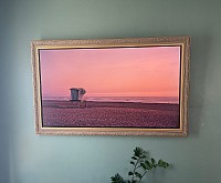 A mounted TV with a frame bezel and a painting of a summer sunset