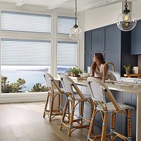 An open concept kitchen with floor to ceiling windows and motorized shades